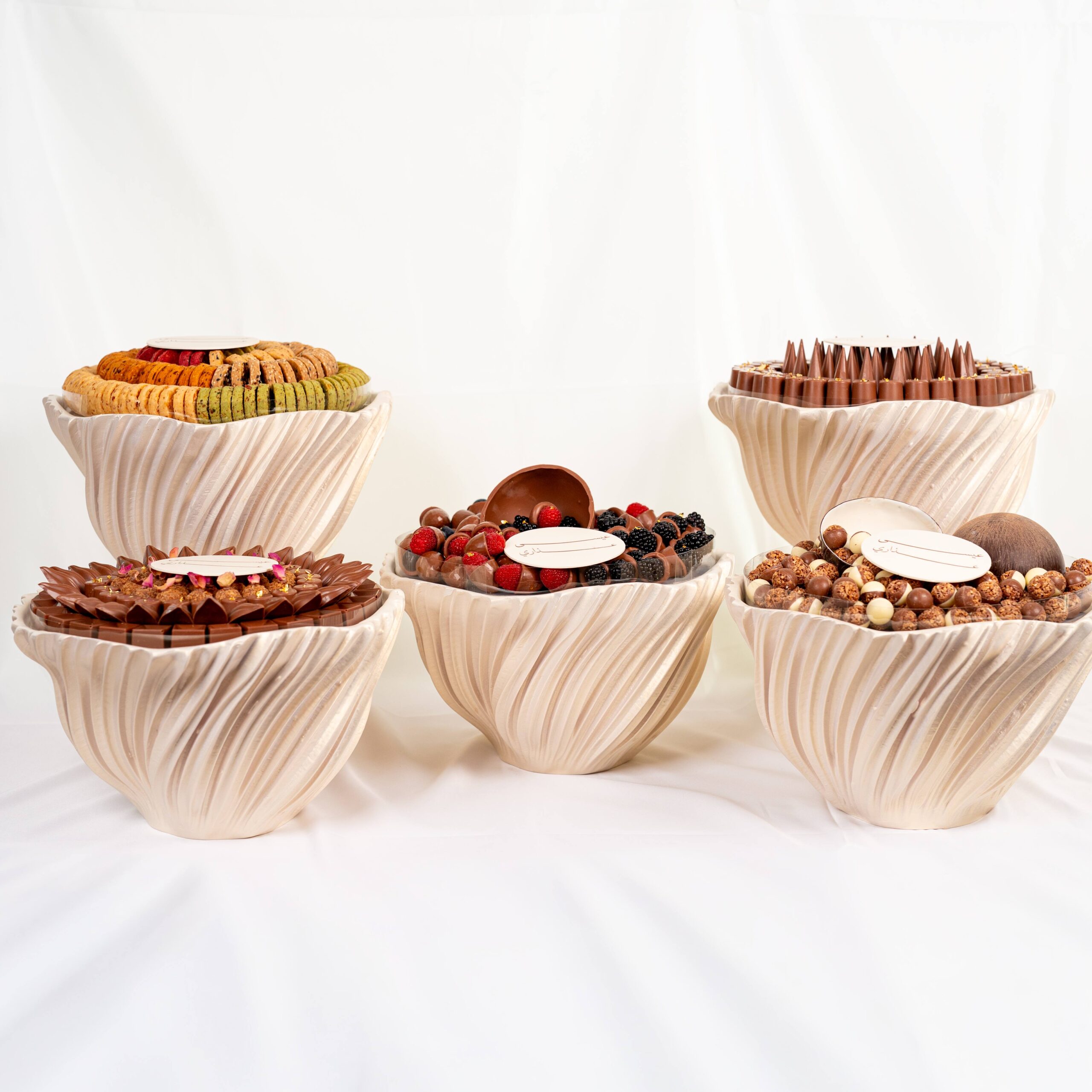 Luxury wedding chocolate collection with assorted chocolates and macarons arranged in elegant round displays