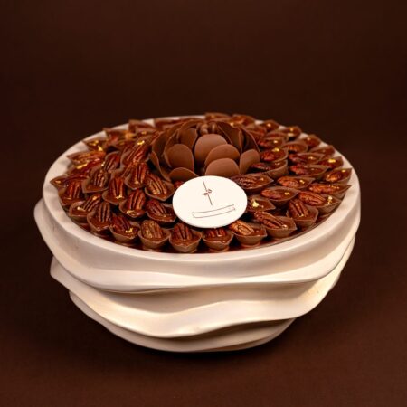 Luxury pecan chocolate tray with milk chocolate cups, whole pecans and a chocolate petal flower on a cream wave stand