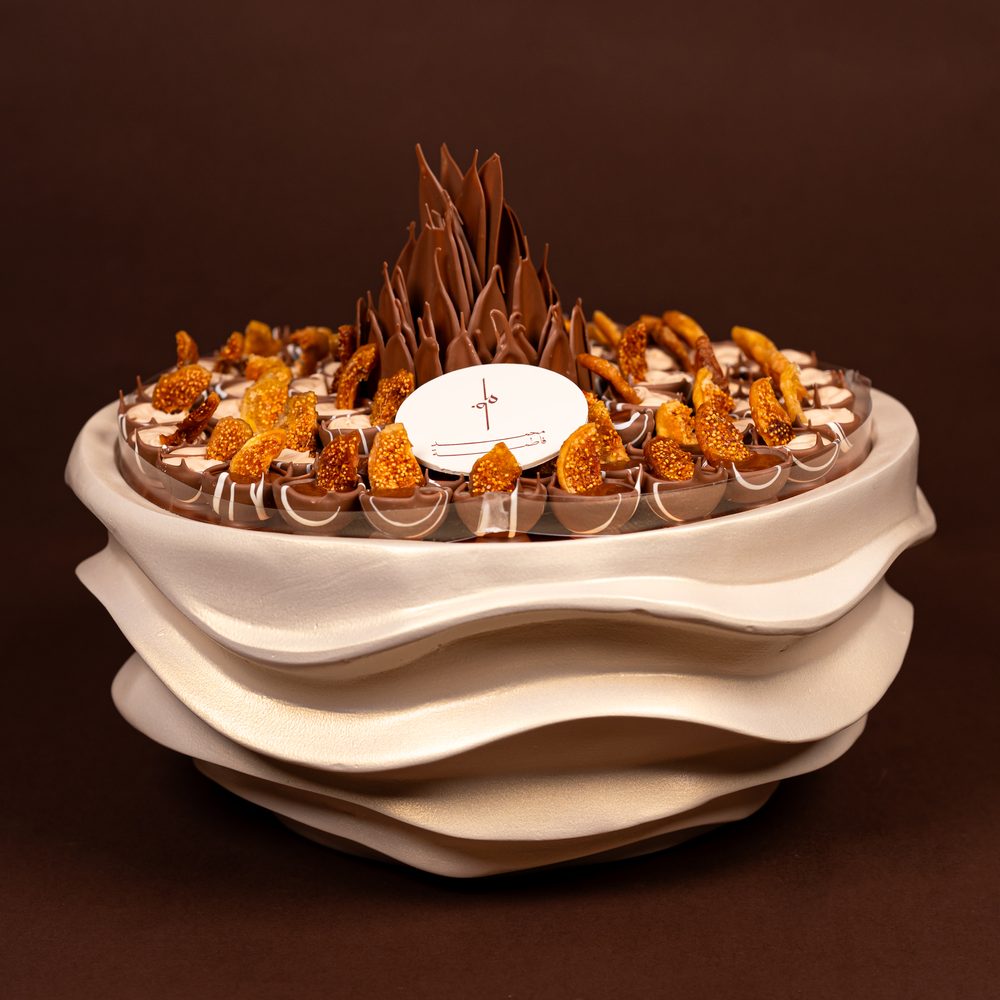 Luxury fig chocolate tray seen from above with cream-filled and chocolate-filled cups topped with dried fig around a chocolate flower