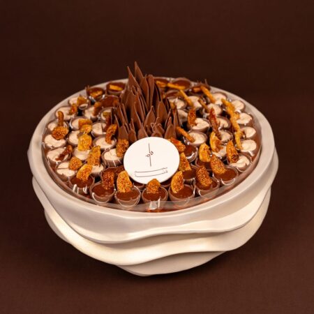 Luxury fig chocolate tray seen from above with cream-filled and chocolate-filled cups topped with dried fig around a chocolate flower
