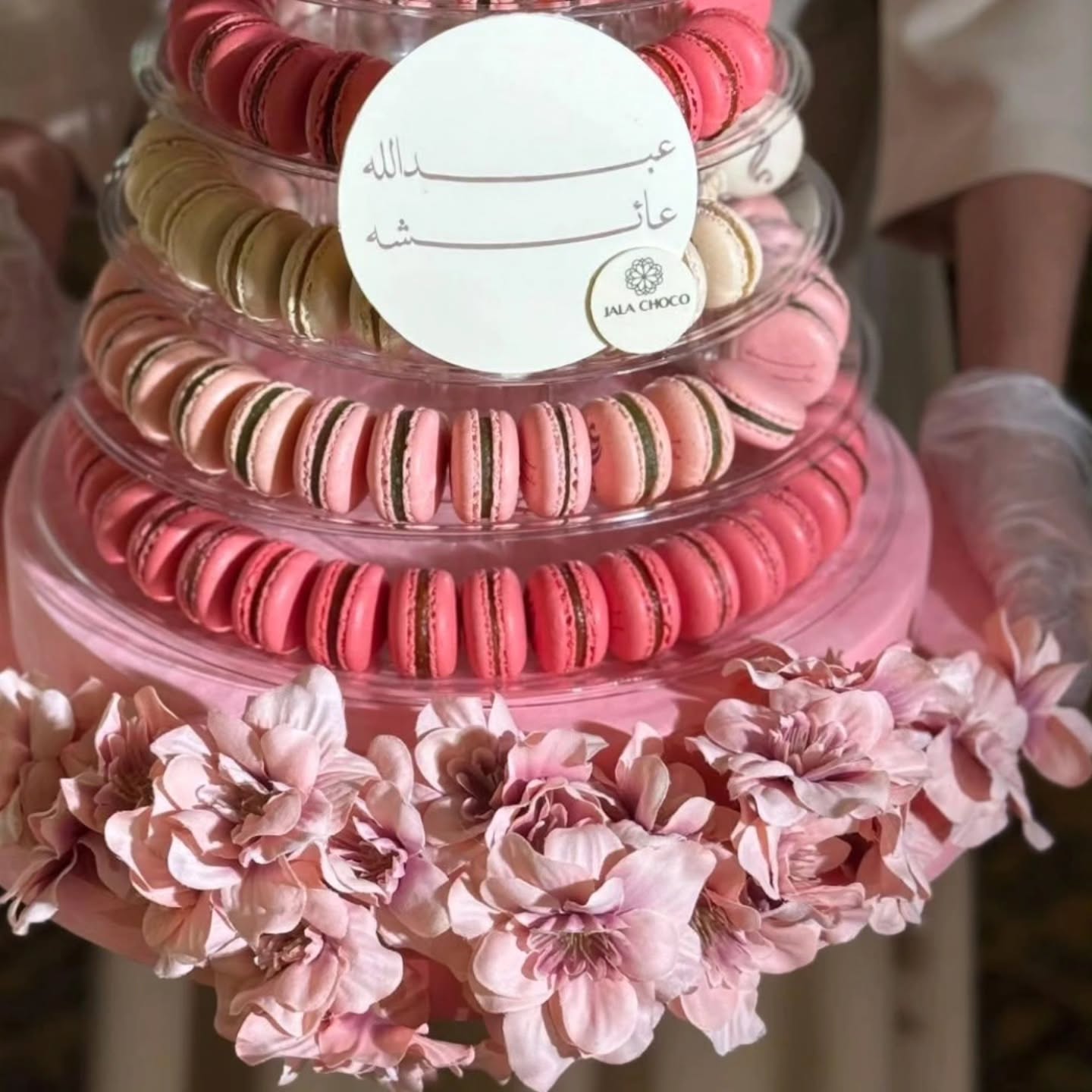 Luxury macaron tower UAE with pink, coral and cream macarons in clear acrylic domes with pink ribbons and flowers