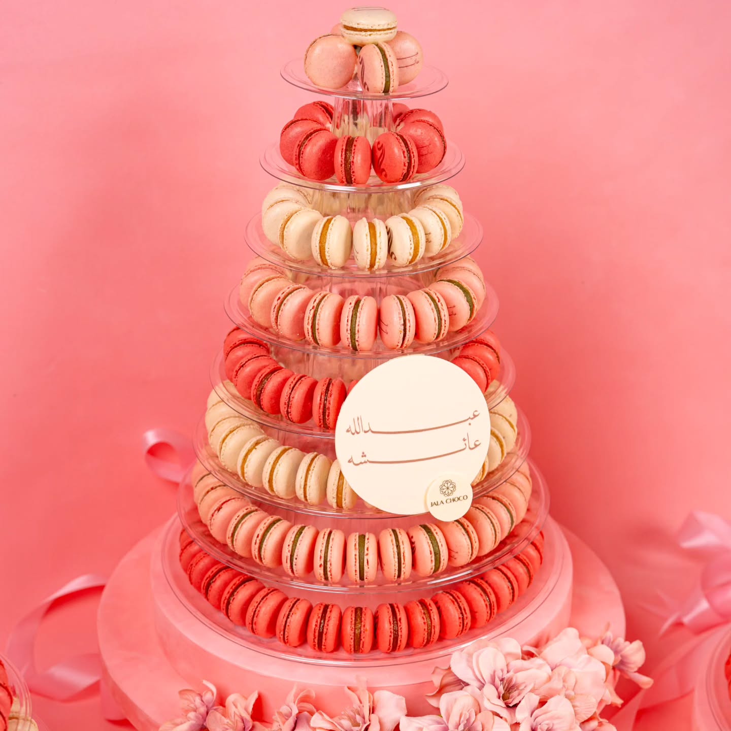 Luxury macaron tower UAE with pink, coral and cream macarons in clear acrylic domes with pink ribbons and flowers