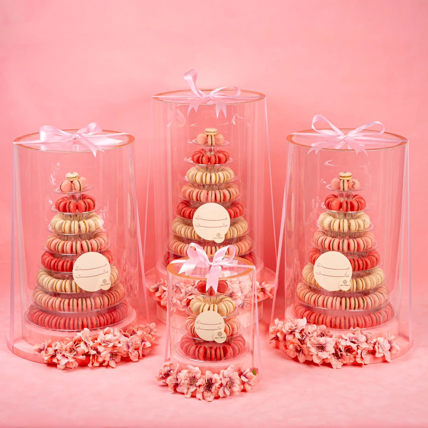 Luxury macaron tower UAE with pink, coral and cream macarons in clear acrylic domes with pink ribbons and flowers