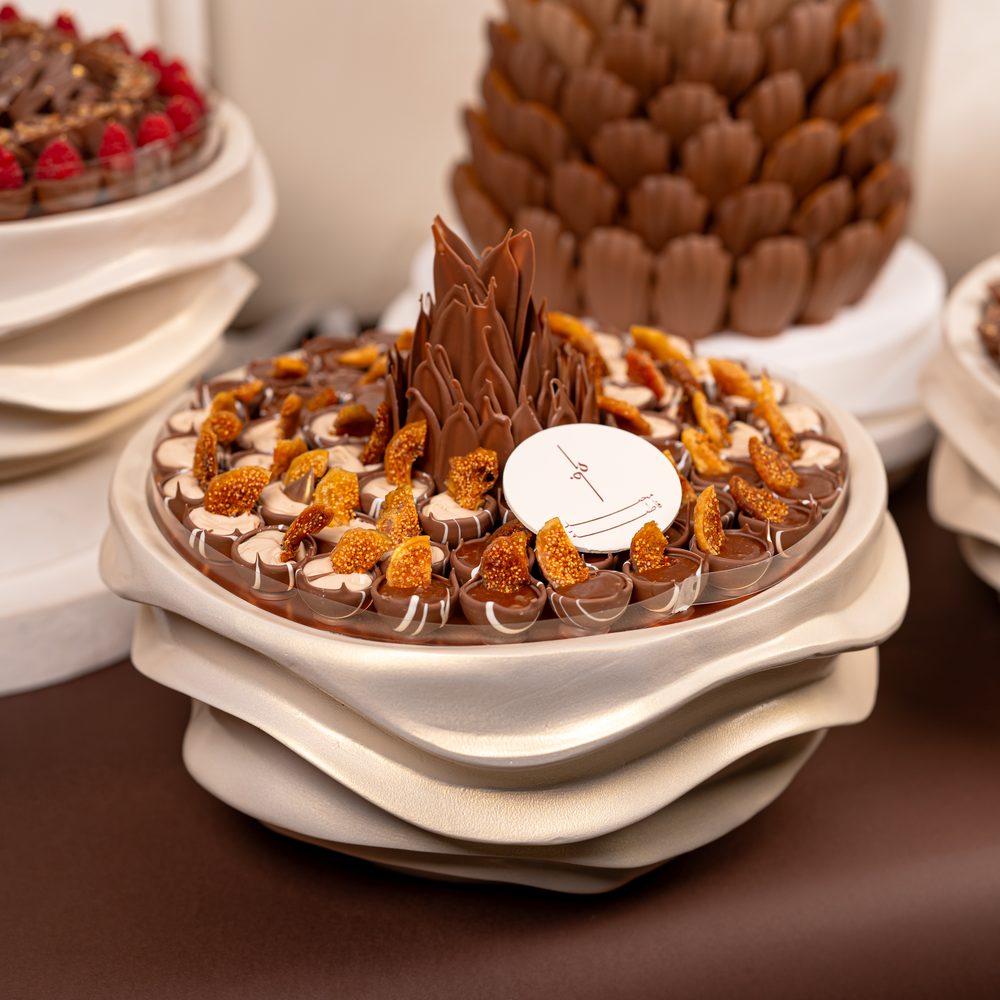 Luxury wedding chocolate set with a tall chocolate cone centrepiece and four cream wave stands holding chocolates and macarons
