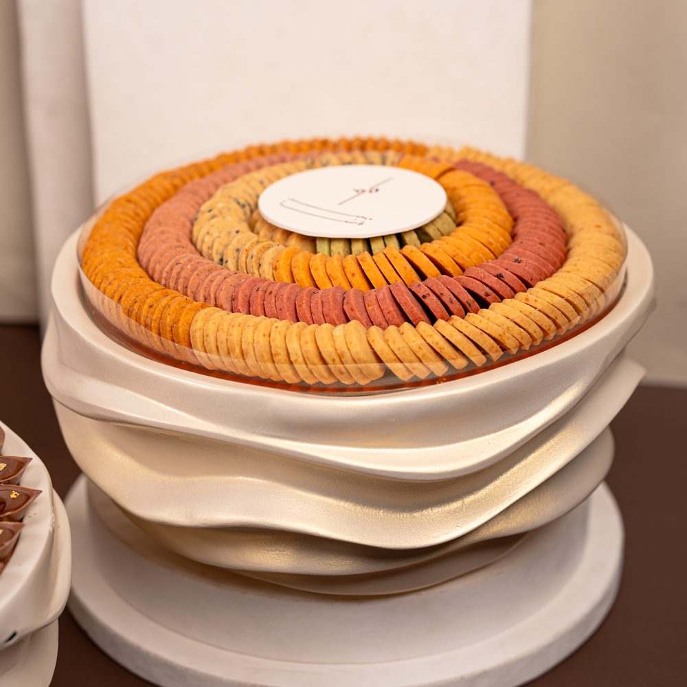 Luxury wedding chocolate set with a tall chocolate cone centrepiece and four cream wave stands holding chocolates and macarons