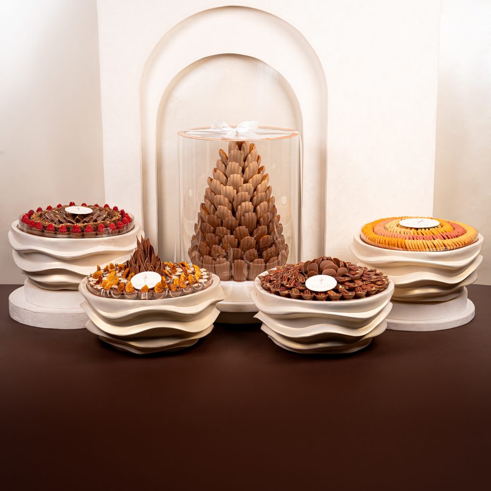 Luxury wedding chocolate set with a tall chocolate cone centrepiece and four cream wave stands holding chocolates and macarons