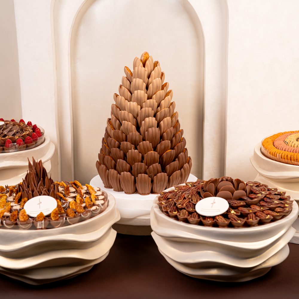 Luxury wedding chocolate set with a tall chocolate cone centrepiece and four cream wave stands holding chocolates and macarons