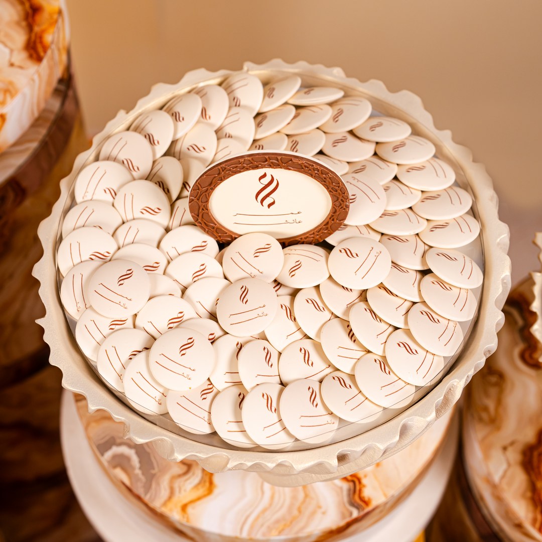 Top view of round white chocolates printed with a brown logo around a framed plaque