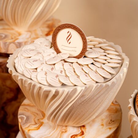 Logo chocolates UAE – white chocolate discs with a printed logo in a sculpted cream bowl